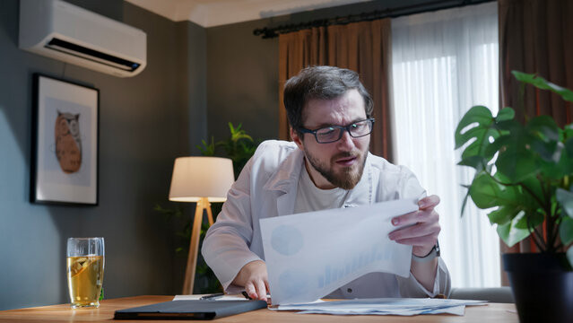 Confused doctor reviewing medical report at desk