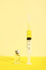 Medical syringe with medicine and ampoule on yellow background