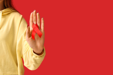 Woman with red ribbon on color background. World AIDS Day concept