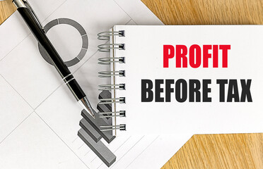 Profit before tax text on notepad with black pen and business charts on wooden desk