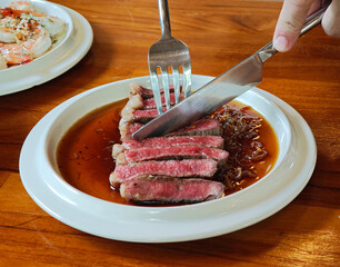 Sliced ​​rib eye steak on white plate, medium rare.