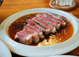 Sliced ​​rib eye steak on white plate, medium rare.