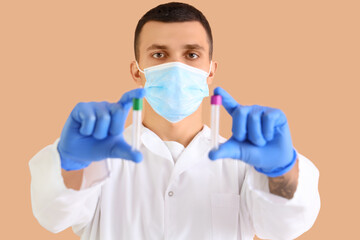 Male doctor in medical mask with test tubes on beige background