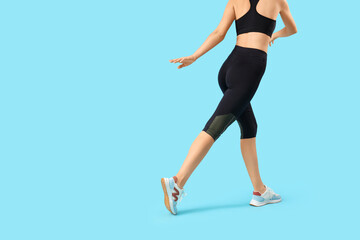 Young woman in black cycling shorts on blue background, back view