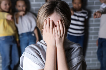 Bullied little boy crying at school, closeup