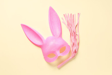 Pink bunny mask with whip on light yellow background