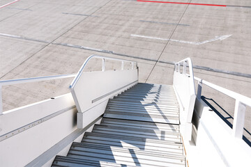 Aircraft stairway stretches upward against a tarmac. Airplane boarding stairs on the runway