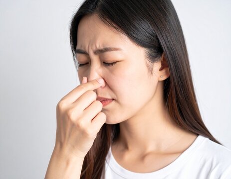 Young woman pinching her nose from an unpleasant smell 不快な臭いに鼻を摘む若い女性