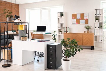 Interior of modern office with desks, shelf units and plants