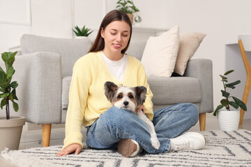 Naklejka na ściany i meble Young woman with her Biewer Terrier dog sitting on carpet at home