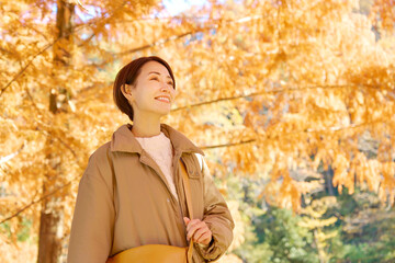 秋の紅葉の中を散歩する女性　ミドルエイジ