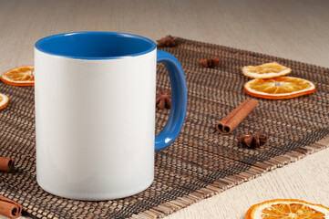 Blank two-tone 11oz mug on on the table. Mug with warm spices like cinnamon, star anise, dried orange. Blue handle. Mug mockup