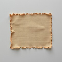 Obraz premium A textured fabric piece with a fringed edge, showcasing a warm, neutral color, ideal for decorative or practical uses.