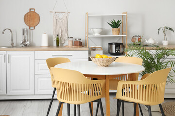 Interior of light kitchen with counters, shelf unit and dining table