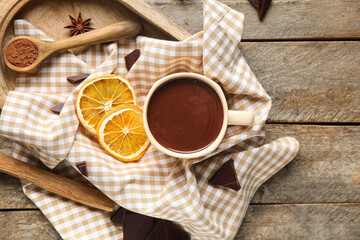 Cup of hot chocolate with cocoa powder, dried orange slices and star anise on wooden background
