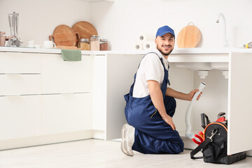 Male plumber repairing sink pipe in kitchen
