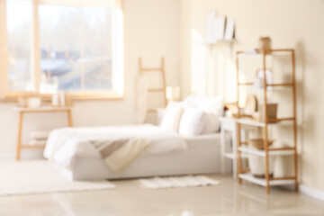 Comfortable bed, shelving unit and frames in interior of bedroom. Blurred view