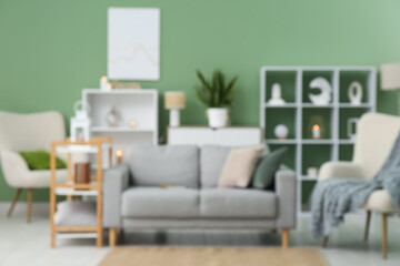 Cozy sofa, armchair and shelving unit in interior of living room. Blurred view