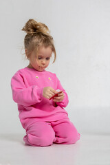 Portrait of cheerful playing girl. Child with smiles and funny emotions on light background. Vertical photo.