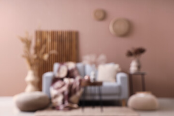 Blurred view of stylish living room with sofa, tables and dry reeds