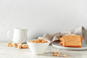 Bowl of tasty peanut butter with nuts on light grunge table