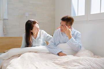 Fototapeta premium ベットの上で頭痛がする中年の男性