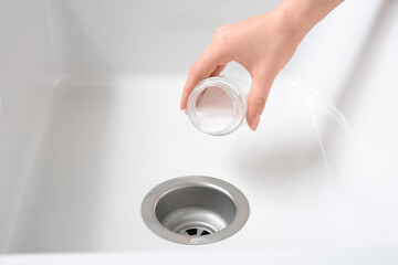Woman cleaning drain with baking soda, closeup