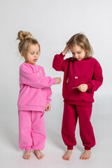 Two funny cute girls playing and having fun. Children with smiles and funny emotions on a light background. Vertical photo. High quality photo