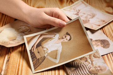 Female hand with old photos of relatives on wooden background. Concept of family tree