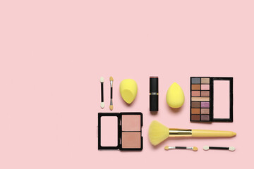 Makeup sponges with yellow brush and different decorative cosmetics on pink background