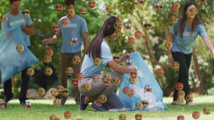 Volunteer team picking litter in sunlit park, initiating floating emoji icons showing green cleanup - Powered by Adobe