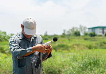 The environmental officer is installing a noise monitoring device outside the factory.