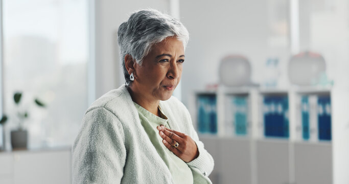 Senior, sick woman and chest pain with infection at hospital for clinic checkup, visit or exam. Mature, female person or heartburn with symptoms for discomfort, acid reflux or viral gastro disease