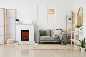 Cozy interior of light living room with fireplace and sofa near white wall