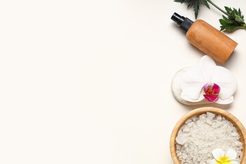 Spa composition with bowl of sea salt, flowers and cosmetic product on light background