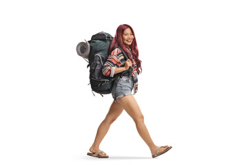 Asian female tourist walking with a backpack and smiling at camera