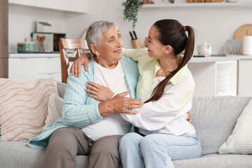 Obraz premium Young woman with her grandmother hugging on sofa at home
