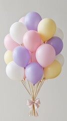 A soft pastel balloon cluster floats against a light neutral background, featuring pink, lavender, cream, and pale yellow tones tied together with a striped pink ribbon. Kids birthday