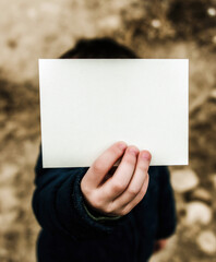 Photo of a white sheet of paper in the hands of a child in front of the camera in white colors.