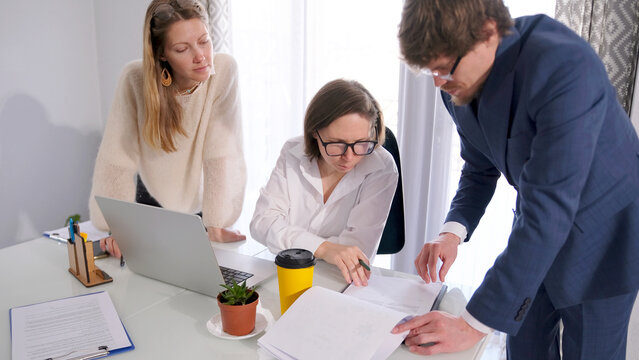 A young businesswoman in glasses and a white shirt examines the documents that the company's lawyer brought her