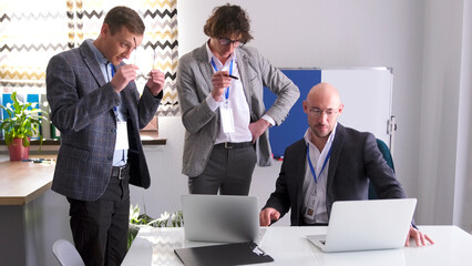 Three professional financiers are discussing the company's development strategy. Men in glasses and suits are working on a common project