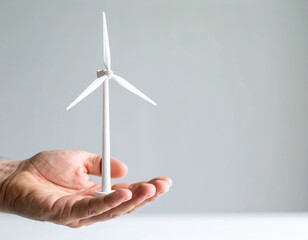 Mano sosteniendo una turbina eólica en miniatura, simbolizando sostenibilidad, innovación y energía limpia.