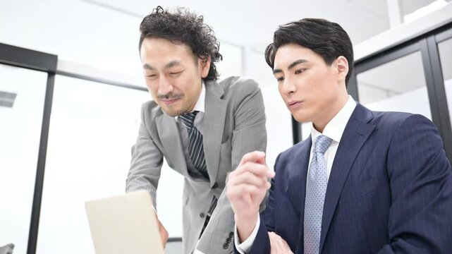 Video of two businessmen in suits having a meeting Boss teaching a newcomer