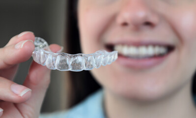 Chica sonríe y muestra férula de contención o retención dental removible para ortodoncia. 