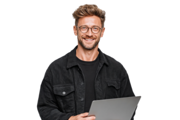 A man wearing glasses and a black jacket is smiling and holding a laptop