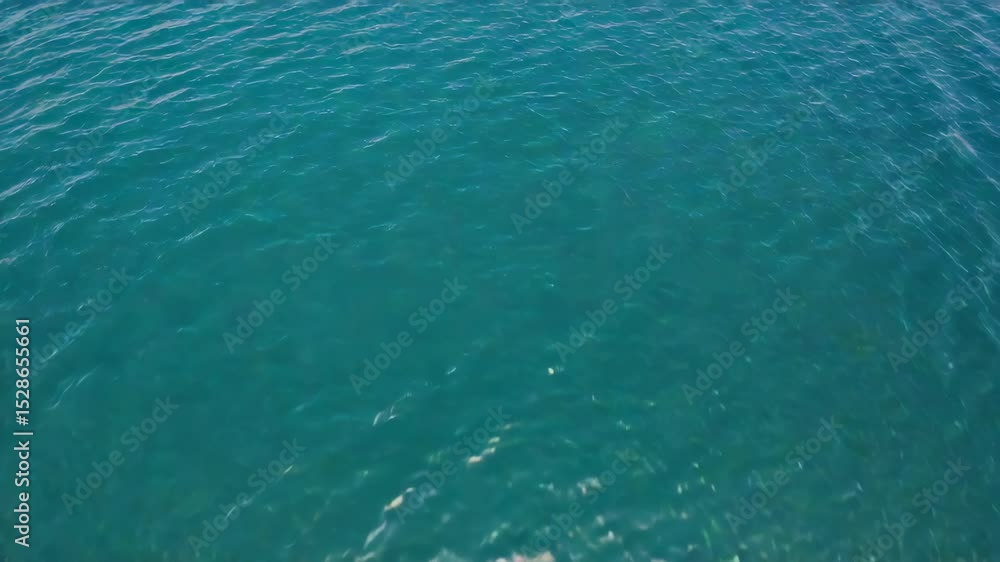 Poster aerial view of tranquil teal water surface creating ripples and reflections with no land in sight