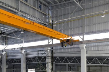Overhead crane in factory or warehouse. Industrial machine or lifting equipment with hoist, hook and wire rope on beam girder structure for manufacturing production and freight shipping transport.