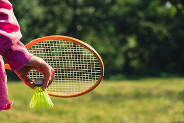 Woman hand holding wooden Badminton racket and shuttlecock. Outside recreation and fresh air....