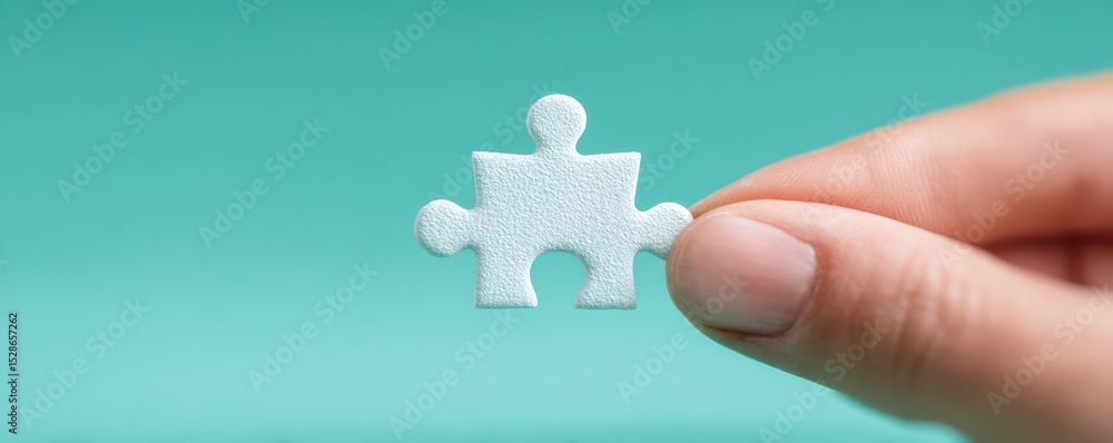 Poster close-up of a hand holding a single white puzzle piece against a mint green background for concepts 