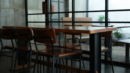 Modern cafe interior with tall windows, concrete floor, with wooden chairs and tables
